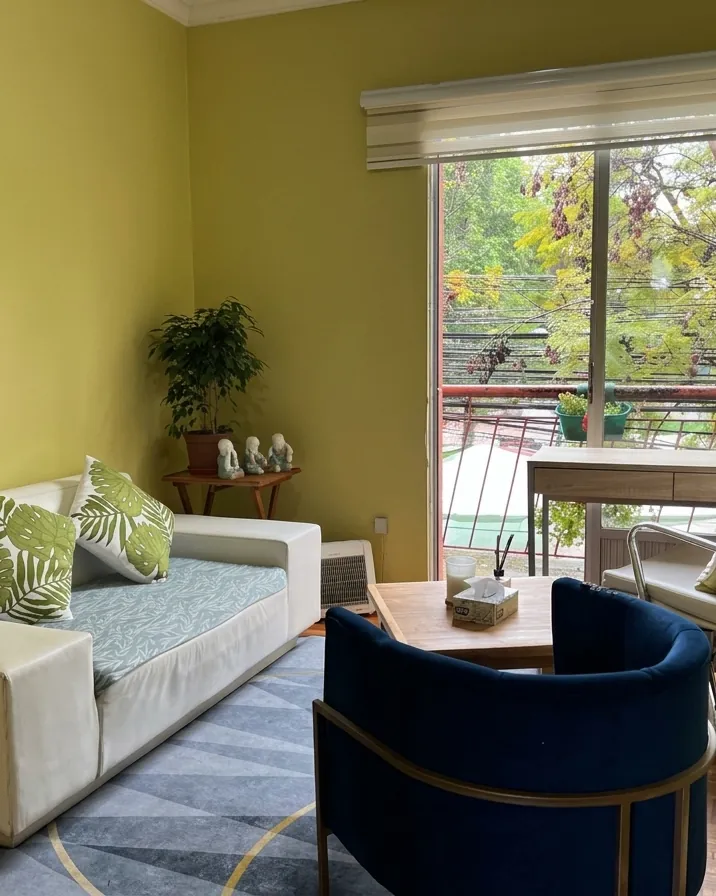 Box de atención de adultos de la Clínica Psicólogos Peñaflor, con sofá, sillón y ventana hacia los árboles