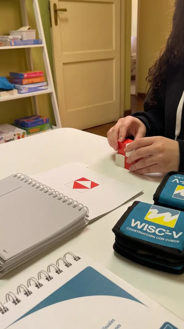 Manos armando un diseño con los cubos rojos y blancos de la prueba Construcción con cubos del WISC-V