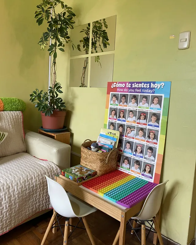 Rincón para niños pequeños en la sala de espera, con mesa, sillas, cuentos y panel ¿Cómo te sientes hoy?