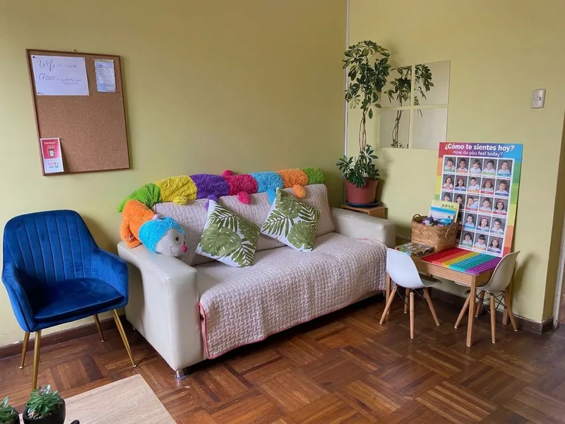 Sala de espera con sofá, cojines, peluches y panel de emociones ¿Cómo te sientes hoy?